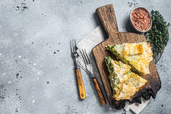 Torta grega Spanakopita com espinafre e queijo em tábua de madeira. Fundo cinzento. Vista superior. Espaço de cópia — Fotografia de Stock