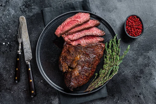 Grilovaný věšák nebo hovězí steak Onglet na talíři s tymiánem. Černé pozadí. Pohled nahoru — Stock fotografie