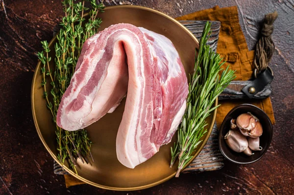 Boerderij vers varkensvlees buik, rauw vlees in een bord met kruiden. Donkere achtergrond. Bovenaanzicht — Stockfoto