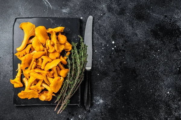 Mermer bir tahtanın üzerinde çiğ Chanterelles mantarı. Siyah arka plan. Üst Manzara. Boşluğu kopyala