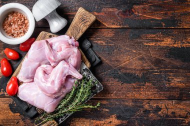 Kekikle kasap tahtasında çiğ tavşan bacağı. Koyu ahşap arka plan. Üst Manzara. Boşluğu kopyala