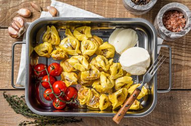 Mutfak tepsisinde Mozzarella peyniri ve domates ile ev yapımı çiğ ravioli. Ahşap arka plan. Üst görünüm