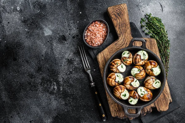 Делікатесенська їжа - Bourgogne Escargot Snails з часником масла в сковороді. Чорний фон. Краєвид. Копіювальний простір — стокове фото