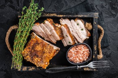 Kızarmış domuz eti göbeği. Baharatlı bir tepside kıtır kıtır kızarmış et. Siyah arka plan. Üst görünüm