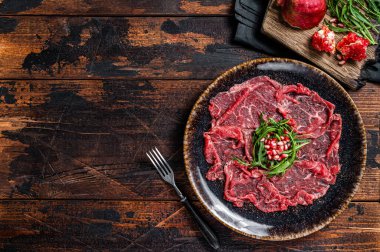 Carpaccio mermer et, roka ve nar tohumlu. Ahşap arka plan. Üst Manzara. Boşluğu kopyala