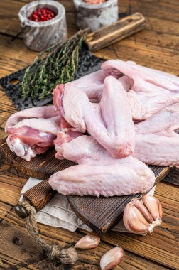 Kasap tahtasında çiğ ördek ya da tavuk kanadı. Koyu ahşap arka plan. Üst görünüm