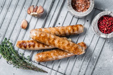 Izgara sucuklu domuz etli sosis ızgarada. Gri arka plan. Üst görünüm
