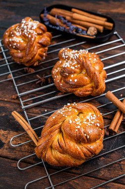 Ev yapımı taze tarçınlı çörek veya rulo, İsveç Kanelbullar. Koyu ahşap arka plan. Üst görünüm