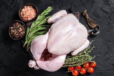 Tahta tahtada kekik ve biberiyeyle pişirilmemiş çiğ tavuk. Siyah arka plan. Üst görünüm