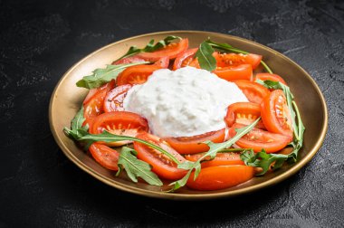 İtalyan salata caprese peynirli stracciatella, domates ve roka. Siyah arka plan. Üst görünüm