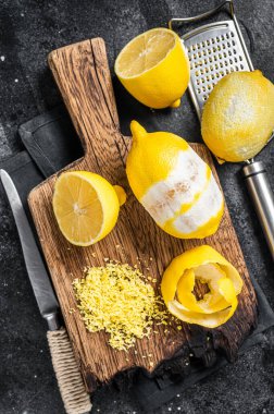 Tahta tahtada rendelenmiş limon ve spiral kabuk. Siyah arka plan. Üst görünüm