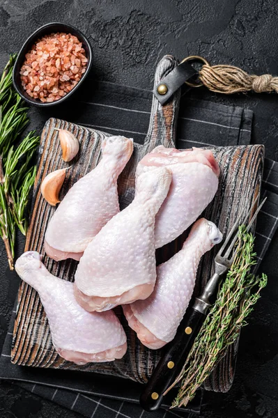 Fresh Raw chicken drumsticks legs on wooden cutting board. Black background. Top view — Stock Photo, Image