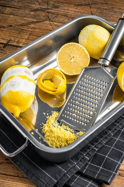 Cozinhar com Lemon Zest ralado e casca em espiral na bandeja da cozinha. Fundo de madeira. Vista superior — Fotografia de Stock