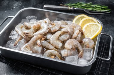 Kuyruğu buzda soyulmuş çiğ Pasifik beyaz karidesi. Siyah arka plan. Üst görünüm