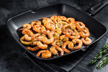 Kızarmış karides, ızgara tavada otlu karides. Siyah arka plan. Üst görünüm