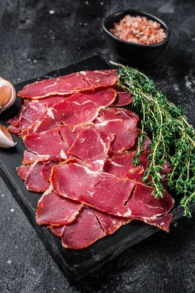 Skivad pastrami rostat nötkött kött med örter. Svart bakgrund. Ovanifrån — Stockfoto