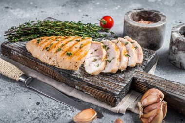 Kesme tahtasında dilimlenmiş hindi ızgara göğüs bifteği. Gri arka plan. Üst görünüm