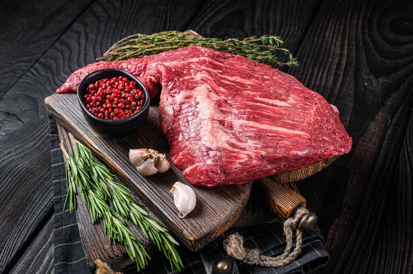 Bife de carne preta angus Tri Tip na tábua de corte com ervas, carne crua. Fundo de madeira preta. Vista superior — Fotografia de Stock
