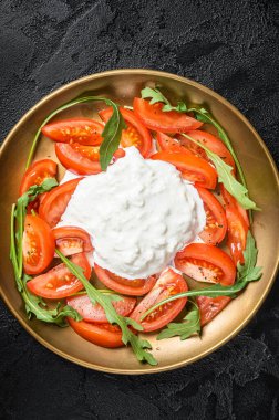 İtalyan salata caprese peynirli stracciatella, domates ve roka. Siyah arka plan. Üst görünüm