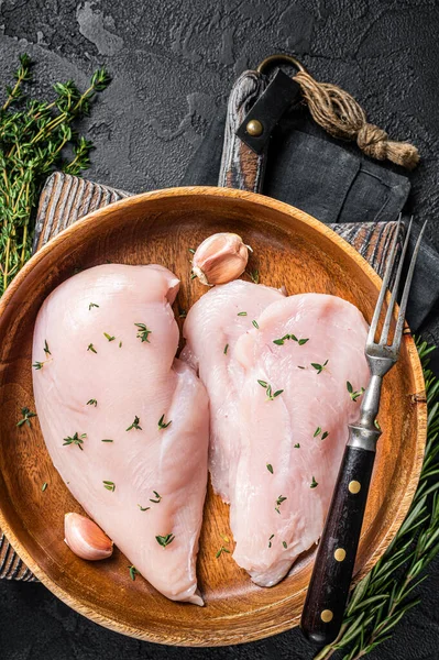 Dilimlenmiş çiğ tavuk göğsü fileto, tavuklu biftekler tabakta. Siyah arka plan. Üst görünüm