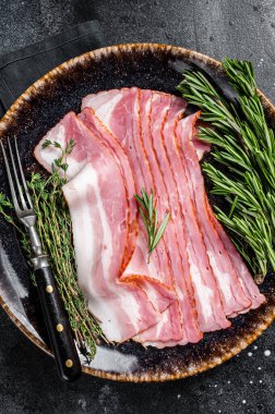 Çiğ domuz pastırması otlarla pişirilmeye hazır. Siyah arka plan. Üst görünüm