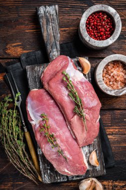 Çiğ ördek göğüsleri, ahşap tahtada tavuk eti biftekleri pişirmeye hazır. Ahşap arka plan. Üst görünüm