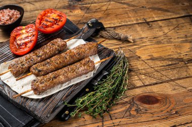 Kızarmış Türk Adana şiş kebabı ızgara domatesle birlikte tahtada. Ahşap arka plan. Üst Manzara. Boşluğu kopyala