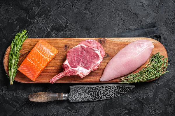 Bifes de carne crua - salmão de peixe, vitela de vaca e peru. Fundo preto. Vista superior — Fotografia de Stock