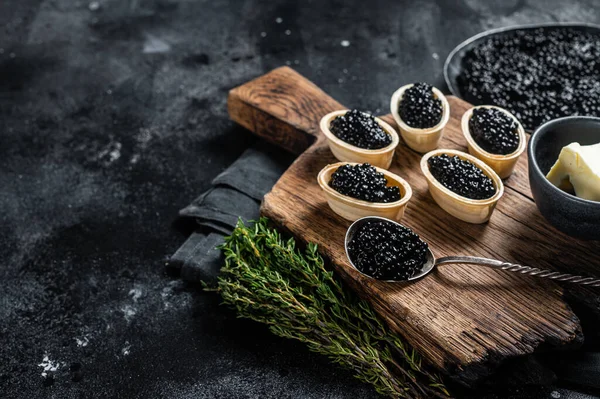 Tartlets com caviar Sturgeon Preto em tábua de madeira. Fundo preto. Vista superior. Espaço de cópia — Fotografia de Stock