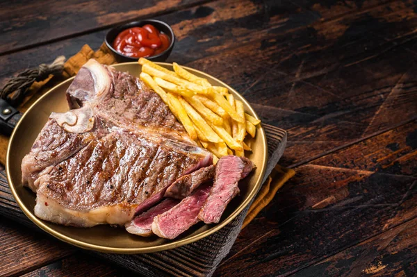Geroosterd Italiaans Florentijns of varkensvlees Biefstuk in een bord met frietjes. Houten achtergrond. Bovenaanzicht. Kopieerruimte — Stockfoto