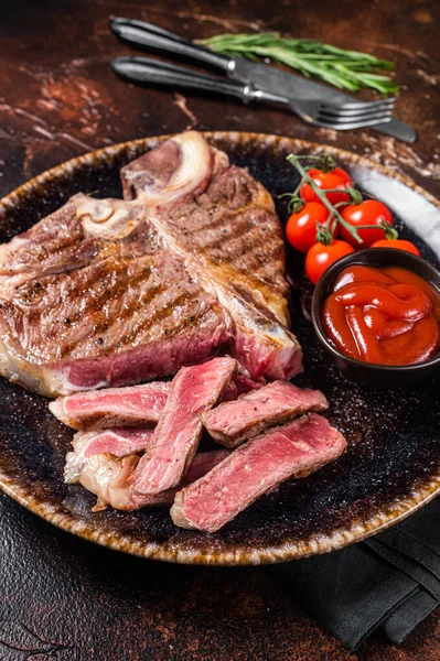 Gegrilde varkensvlees rundvlees Steak, gekookt t bot in een bord met tomaat. Donkere achtergrond. Bovenaanzicht — Stockfoto