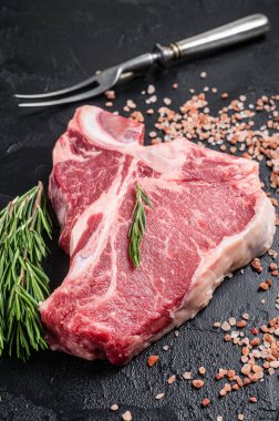 Çiğ biftek biftek, kasap masasında biftek ve biberiye. Siyah arka plan. Üst görünüm