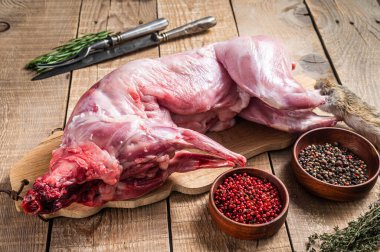 Çiğ yaban tavşanı, tahta tahtada otlu taze et. Ahşap arka plan. Üst görünüm