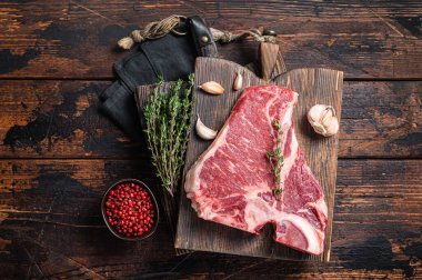 Biftekli biftek, kasap panosunda çiğ biftek ve şifalı otlar. Ahşap arka plan. Üst görünüm