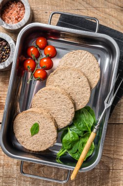 Bitki temelli etten yapılmış çiğ et köfteleri mutfak tepsisinde otlu taze vegan burger pirzolası. Ahşap arka plan. Üst görünüm