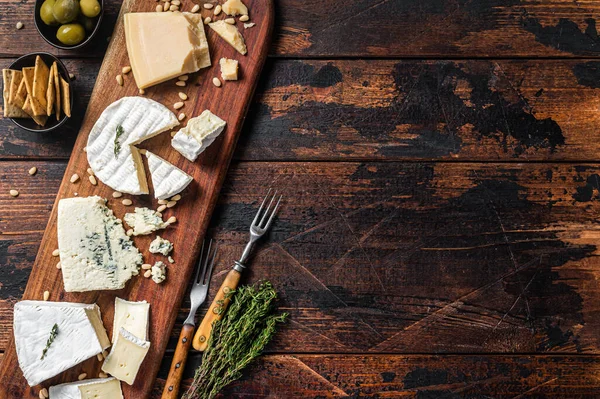 Prato de queijo com camembert, brie, Gorgonzola, parmesão, azeitonas, nozes e bolachas. Fundo de madeira. Vista superior. Espaço de cópia — Fotografia de Stock