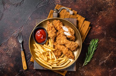 Patates kızartması ve tabakta domates ketçaplı kızarmış tavuk eti. Karanlık arka plan. Üst görünüm