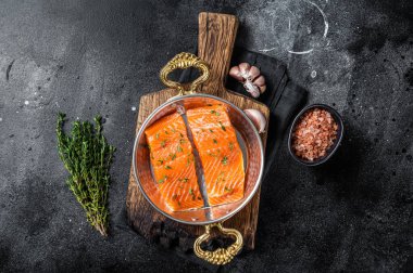 Pişmemiş somon fileto biftekleri, pişmeye hazır tavada çiğ organik balık. Siyah arka plan. Üst görünüm