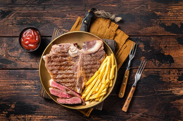 Pečené italské florentské nebo porterhouse hovězí maso Steak na talíři s hranolky. Dřevěné pozadí. Horní pohled — Stock fotografie