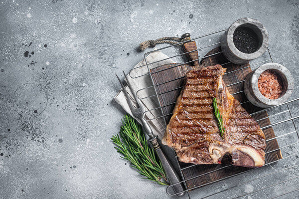 Grilled t-bone porterhouse beef meat Steak on a grill with spices. Gray background. Top view. Copy space