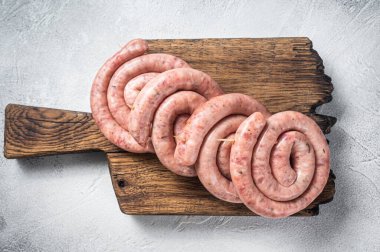 Tahta bir tahtanın üzerinde çiğ domuz eti sosisi pişirmeye hazır. Beyaz arka plan. Üst görünüm