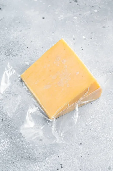 Organický ostrý čedar Sýr ve vakuovém balení. Šedé pozadí. Horní pohled — Stock fotografie