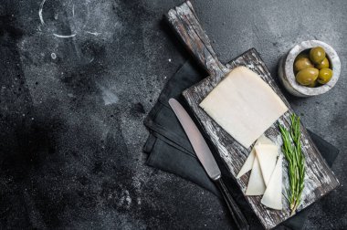 Tahta kesme tahtasına dilimlenmiş Hollanda keçi peyniri. Siyah arka plan. Üst Manzara. Boşluğu kopyala