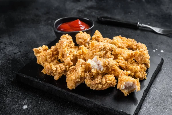 Kızarmış kızarmış ekmek kırıntısı, tavukla kaplı ketçaplı patlamış mısır. Siyah arka plan. Üst görünüm