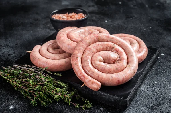 Geleneksel çiğ sosisler mermer bir tahtanın üzerinde kekik ile. Siyah arka plan. Üst görünüm