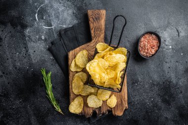 Sepette deniz tuzu ve biberiyeli patates cipsi. Karanlık arka plan. Üst görünüm