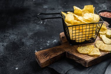 Sepette deniz tuzu ve biberiyeli patates cipsi. Karanlık arka plan. Üst Manzara. Boşluğu kopyala