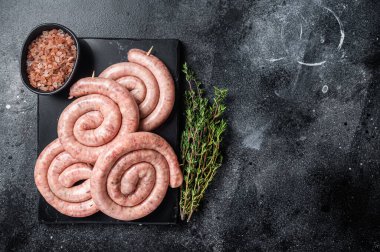 Geleneksel çiğ sosisler mermer bir tahtanın üzerinde kekik ile. Siyah arka plan. Üst Manzara. Boşluğu kopyala