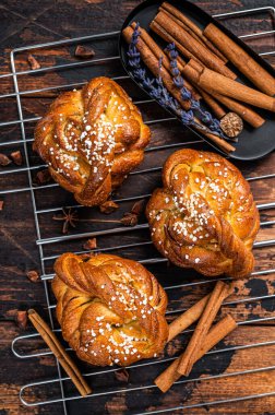 Ev yapımı taze tarçınlı çörek veya rulo, İsveç Kanelbullar. Koyu ahşap arka plan. Üst görünüm