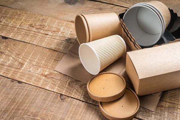 Tek kullanımlık kağıt sofra takımı. Çevre dostu geri dönüşüm seti kağıt bardaklar, tabaklar, çanta, fast food kapları ve çatal bıçak takımı. Ahşap arka plan. Üst Manzara. Boşluğu kopyala